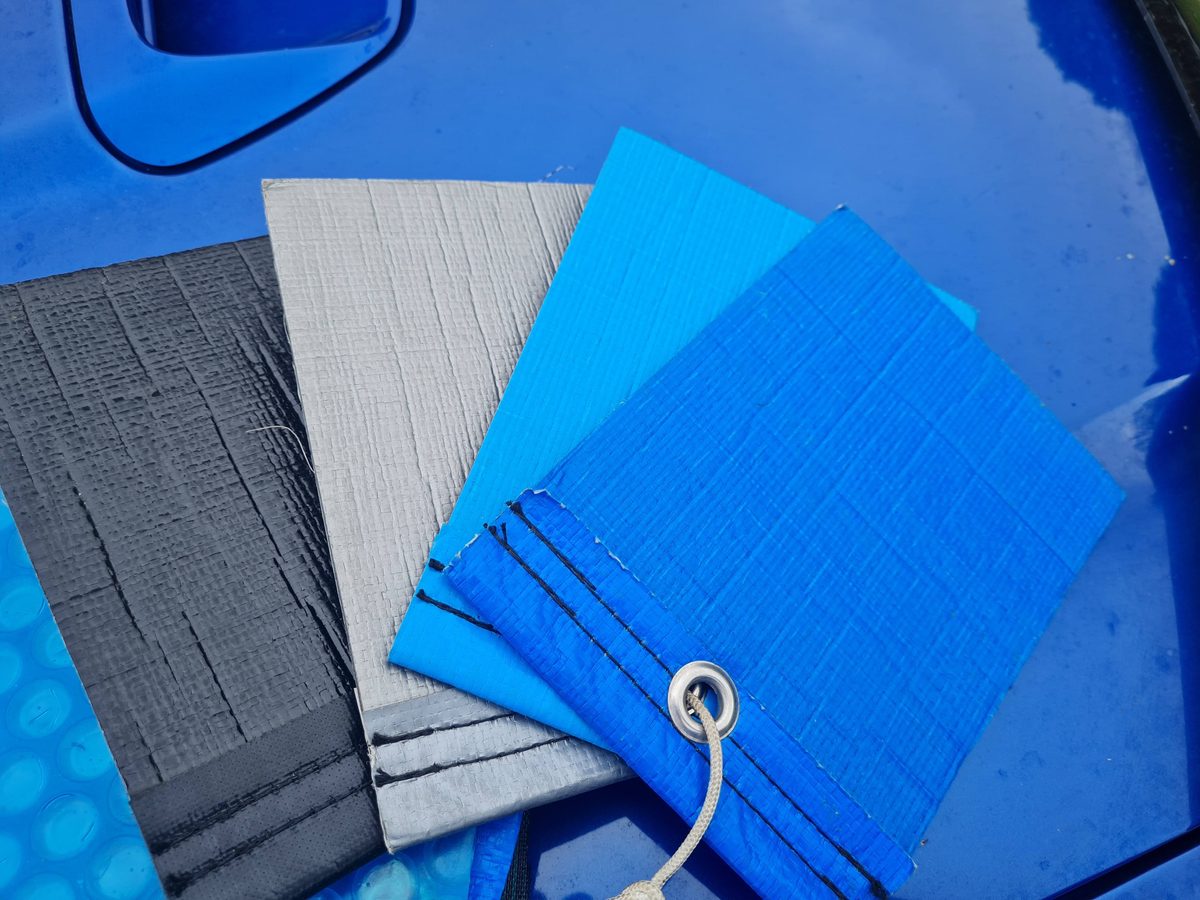 Pool liner samples in grey, light blue and dark blue laid on a pool cover