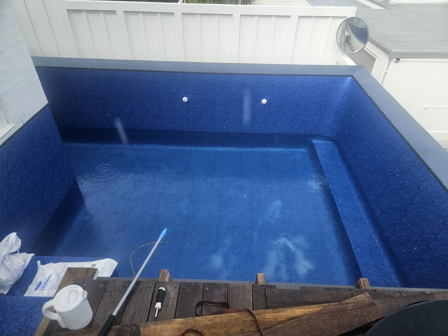 A small rectangular pool with a dark blue liner and a built-in step
