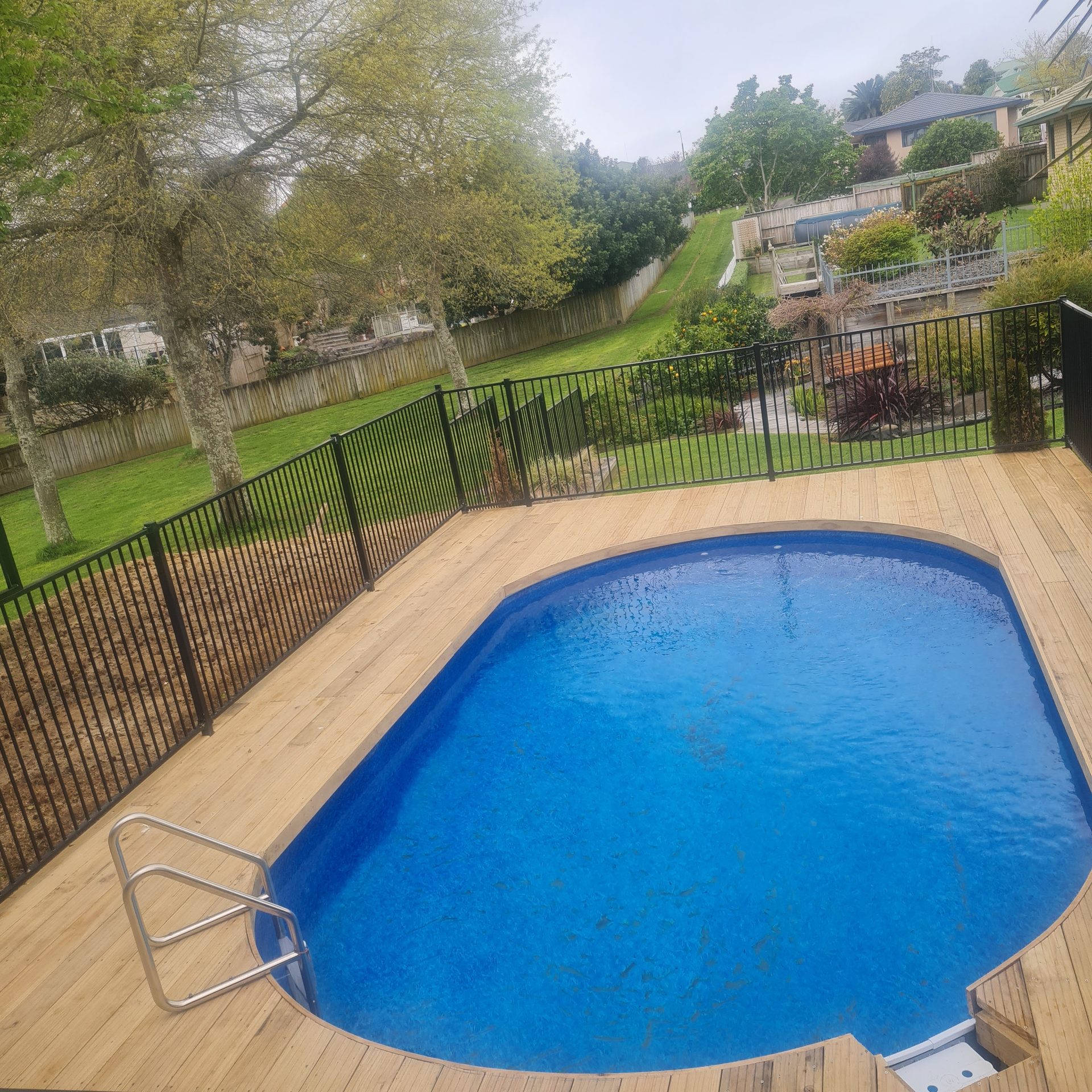 A blue liner pool set into a new timber deck, with a stainless steel ladder at one end