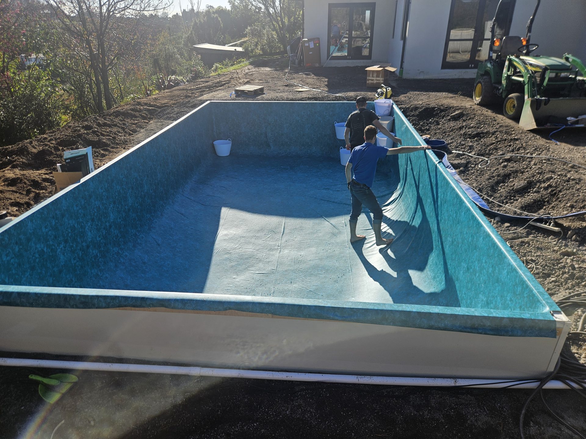Two men fitting a patterned liner inside a new rectangular pool