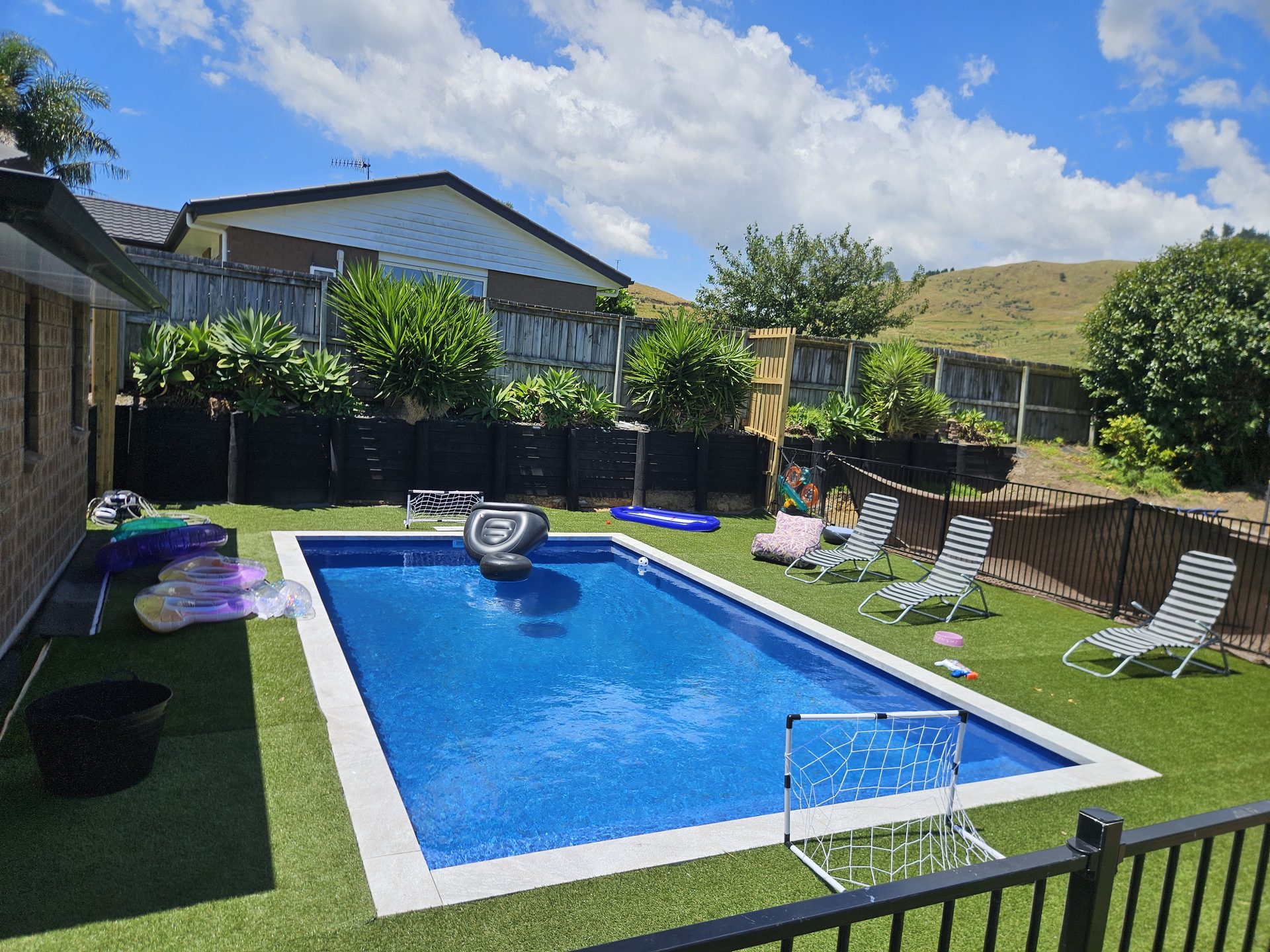 A small backyard swimming pool with artificial grass surrounding it in Tauranga New Zealand