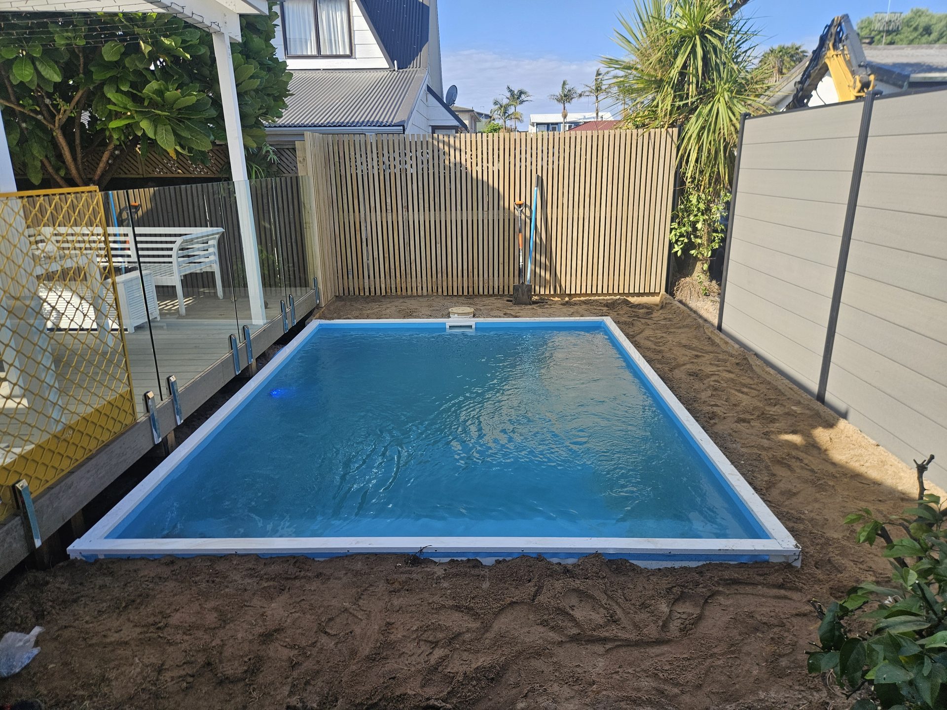 A small swimming pool being built into a small space in a back yard in Tauranga